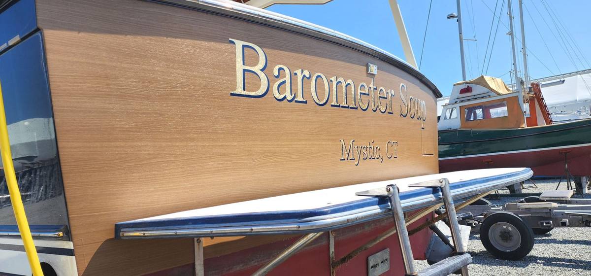 Barometer Soup gold vinyl boat name lettering on a wooden transom