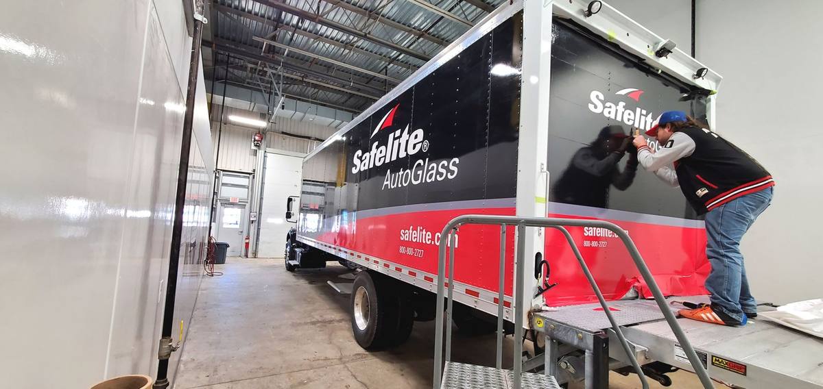 Installer applying Safelite AutoGlass wrap to a box truck