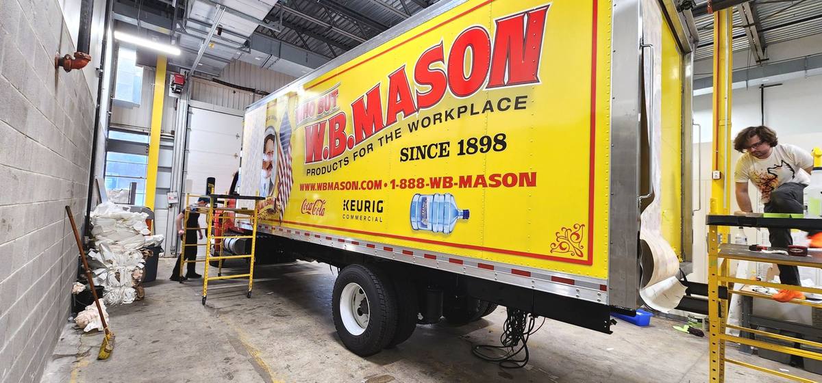 W.B. Mason yellow box truck graphics being installed in the shop